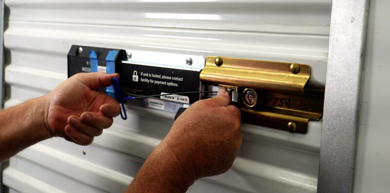 A photo of an authorized dealer installing an Electronic Lock for Self Storage on a white unit door.